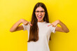 © Asier - Young caucasian woman isolated on yellow background surprised pointing with finger, smiling broadly.