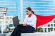 a surprised woman with a superhero cape looks at her laptop