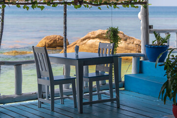 Wall Mural - Wooden table and chairs in tropical beach cafe near sea water, island Koh Phangan, Thailand