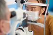 © DragonImages - Optometrist using slit lamp to view structures of patients eye such as cornea, iris, and lens during exam