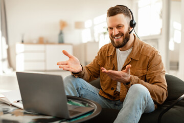 Man Using Laptop Making Video Call Wearing Headset At Home