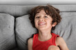 © Lisa Tichané - Portrait of young boy smiling on grey couch