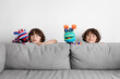 © Lisa Tichané - Funny twin brothers making puppet show behind couch