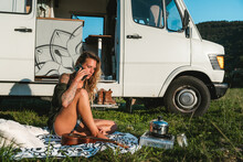 Woman Talking On Smartphone Near Camping Van