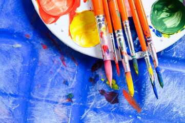 Top view of painters brushes on plastic palette with colorful watercolour. Copy space