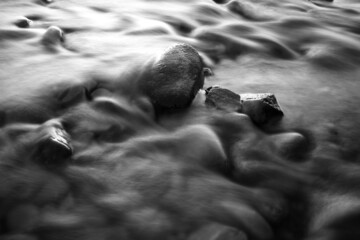 River water flowing trough the stones long exposure silky water effect black and white