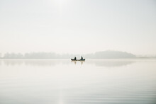Two Men In A Canoe On Vast Calm Water Surface Of The Lake, Sunny Day