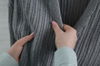 © New Africa - Woman touching clothes made of soft knitted fabric, closeup