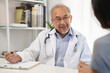 © Pormezz - Close up doctor talking with the patient at a desk in the clinic