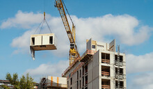 Crane Lifting A Wooden Building Module To Its Position In The Structure. Construction Site Of An Office Building In Berlin. The New Structure Will Be Built In Modular Timber Construction.