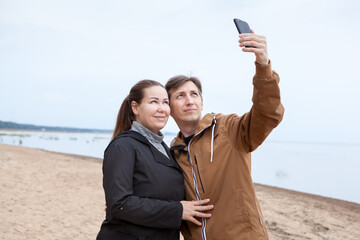 Loving cheerful happy couple taking selfie at the sandy beach