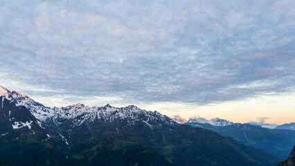 Wall Mural - Scenic view of beautiful landscape in Swiss Alps. Fresh green meadows and snow-capped mountain tops in the background in springtime, Switzerland.