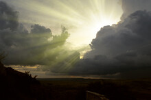 Cloudscape Image Of Dark Stormy Clouds In Blue Sky With Sun Beam. The Rays Of The Sun After The Rain. Scenery With The Sun's Rays Filtering Through The Gray Clouds. Dramatic Sky As The Sun Hides 