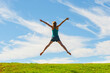 © Matthew - Happy woman jumping for joy, celebrating winning and enjoying happiness of freedom and carefree lifestyle on green grass with blue sky, background with copy space
