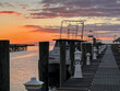 A colorful orange sunrise over the pier in Apalachicola, Florida with old, docked boats.