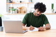 © kucherav - Indian young man using laptop for watching webinar, studying online and takes notes in a notebook, male student is studying online, e-learning concept