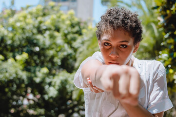 strong young brunette woman from the front, punching with a clenched fist and looking at the camera