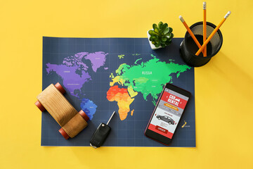 Wall Mural - Mobile phone with open car rent app, wooden toy, key, stationery and map on yellow background