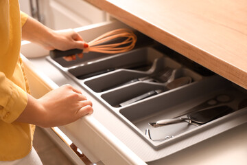 Woman taking whisk from drawer in kitchen, closeup