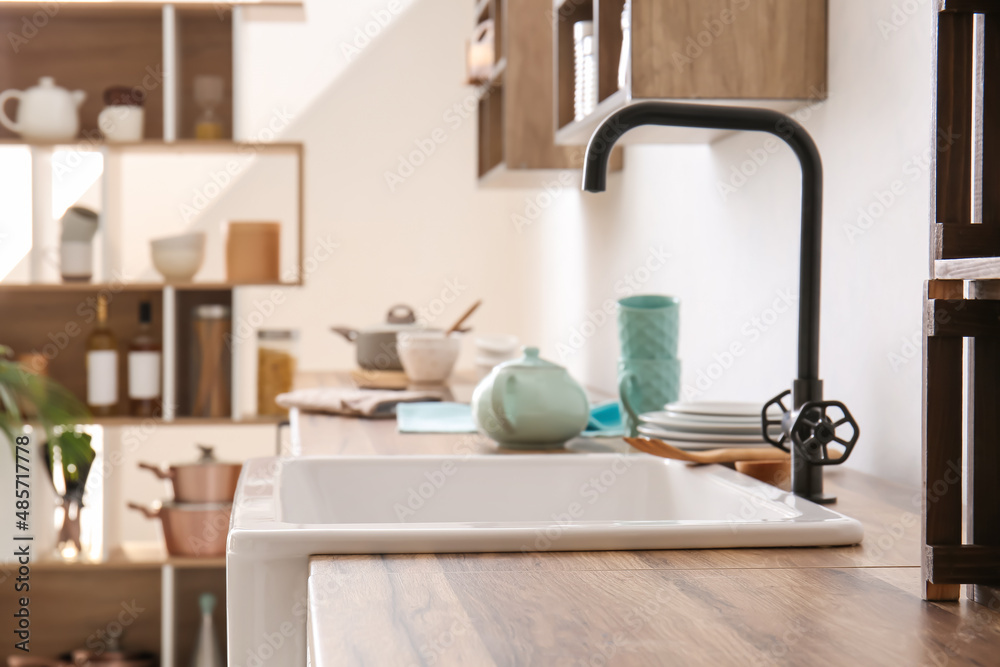 Wooden table top and sink near light wall in kitchen