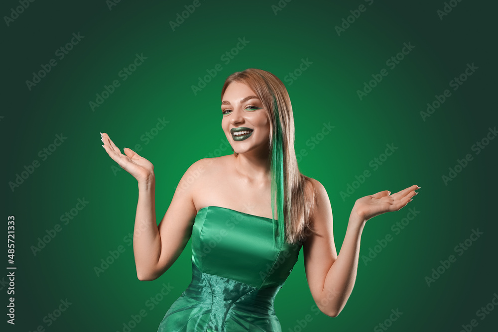 Beautiful young woman with unusual makeup for St. Patrick's Day on green background