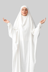 Wall Mural - Muslim woman praying on light background