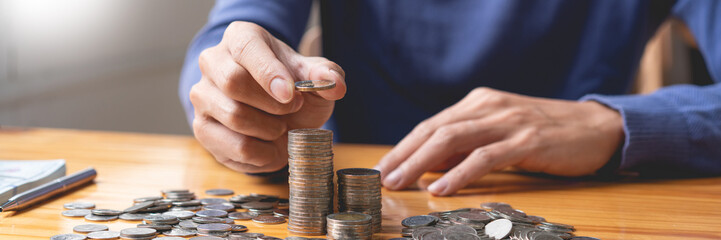 saving concept the guy who wears deep blue pullover counting his saving coins by pile them up