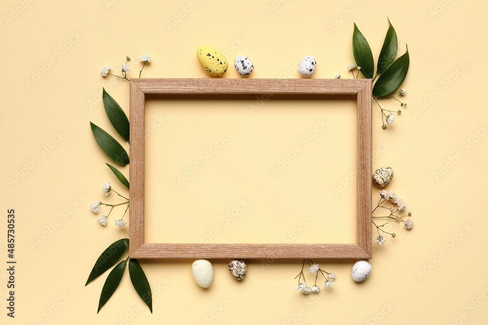 Easter composition with blank photo frame, eggs and flowers on beige background