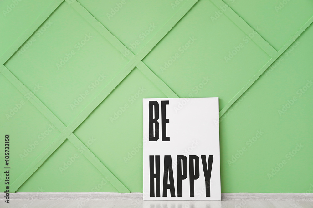 Poster with text BE HAPPY near color wall