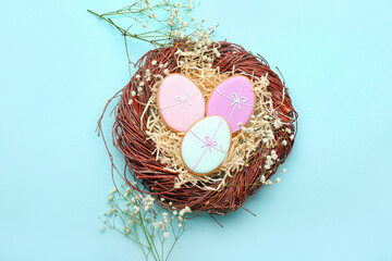 Poster - Nest with creative Easter cookies and flowers on blue background