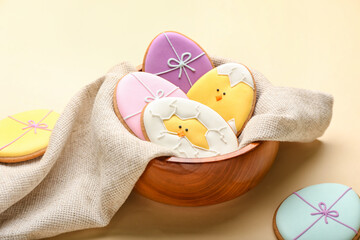 Poster - Bowl with creative Easter cookies on beige background, closeup