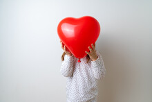 Caucasian Pretty Toddler Girl Plays With Heart Shape Balloon On White Studio Background 