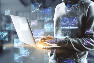 Canvas Print - Hacker in hoodie using laptop with various forex screens on blurry office interior wallpaper. Cryptocurrency, hacking, bticoin trading and finance concept. Double exposure.