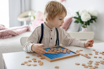 Preschool child, cute blond boy, playing with wooden numbers