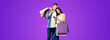 Love, holiday sales, shop, retail, consumer concept - happy couple with shopping bags, looking at mobile phone. Valentines Day holiday. Purple violet color background.