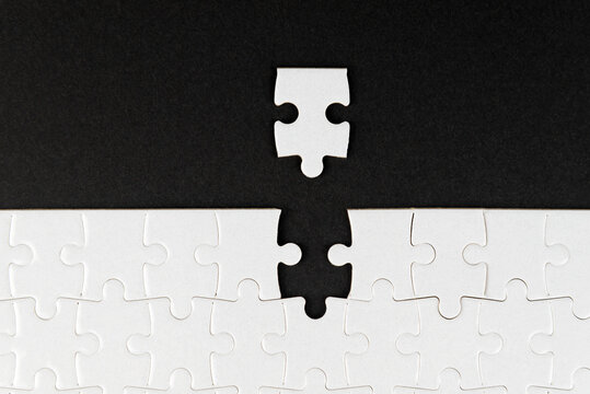Wall Mural -  - White puzzle with missing piece on black background. Business concept. Finish what you start. Team work and partnership. Blank white and black jigsaw puzzle background