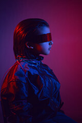 Wall Mural - portrait cyberpunk boy child in vr glasses in blue and red tones with wires on a red background