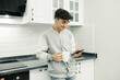 © platinumArt - Teenager, young teenager leaning on kitchen counter smiling looking at phone in hand, smiling teenager holding coffee mug. Selective focus, noise effect.