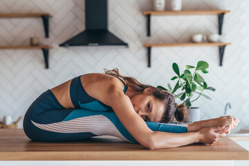 Wall Mural - Fit woman exercising at home, seated forward fold