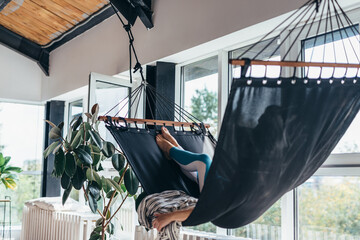 Wall Mural - Woman is lying at home in a hammock and resting