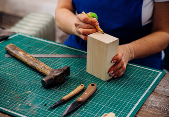 A female carpenter cuts wood with a knife in a carpentry or makeshift workshop. Dust and shavings scatter in the air.Workplace.