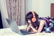 © gmstockstudio - Little girl using the laptop with earphones