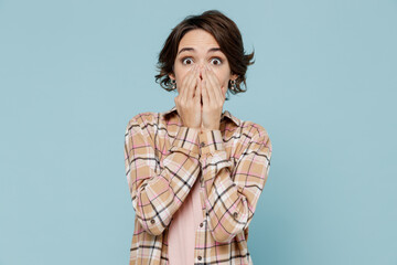 Wall Mural - Young shocked surprised amazed astonished woman 20s wearing casual brown shirt cover mouth with hand isolated on pastel plain light blue color background studio portrait. People lifestyle concept