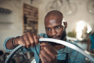 Aufkleber - This spoke keeps popping out. Shot of a handsome young man standing alone in his shop and repairing a bicycle wheel.