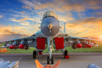 Wall Mural - Fighter with covered engines and live ammunition on the wings in the parking lot during sunset.