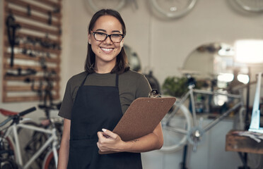 Sticker - Just finished up with a stocktake. Shot of an attractive young woman standing alone in her bicycle shop and holding a clipboard.