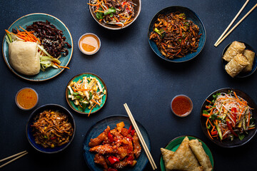 Wall Mural - Set of Chinese dishes on table: sweet and sour chicken, fried spring rolls, noodles, rice, steamed buns with bbq glazed pork, Asian style banquet or buffet, top view with copy space
