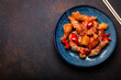Chinese traditional wok dish sweet and sour deep fried chicken with vegetables stir-fry on plate with sesame seeds on rustic dark concrete background top view, Asian meal with chopsticks copy space

