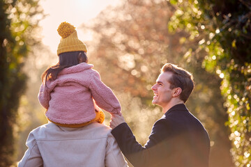 Wall Mural - Rear View Of Family With Two Dads On Walk In Winter Countryside Carrying Daughter On Shoulders