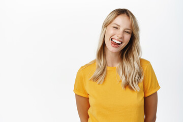 Wall Mural - Happy people. Beautiful girl smiling and showing white perfect teeth, laughing carefree, standing in yellow tshirt over white background